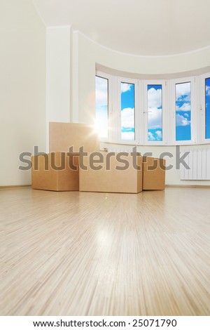 Heap of boxes in an empty living room against a window