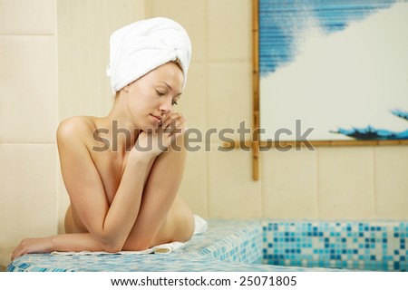 The woman with a towel on a head lies on the brink of pool