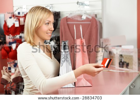 The blonde with packages in an underwear boutique holds a credit card in a hand