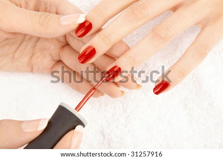 The female hand puts a varnish on nails of the female fingers, isolated