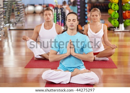 Three persons sit in a lotus pose