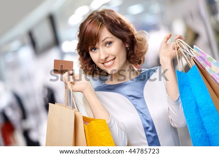Portrait of the young beautiful woman smiling in shop with bags and a credit card