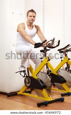 Young man trains on a velosimulator in sports club