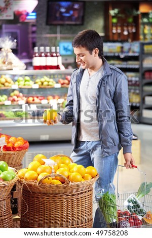 The man with a basket of products chooses a grapefruit in shop
