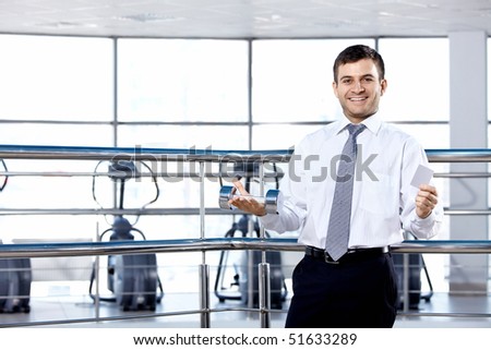 The young man from dumbbells and the card against gym apparatus