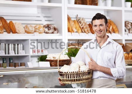 The young seller holds a basket with cakes in shop