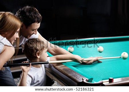 The young couple and the child plays billiards