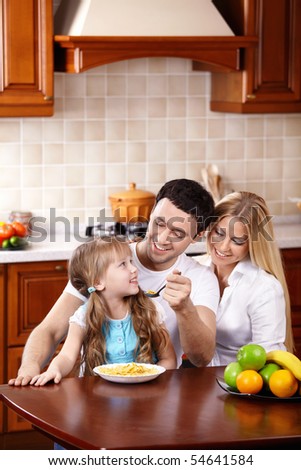 The father feeds the daughter from a spoon with a breakfast