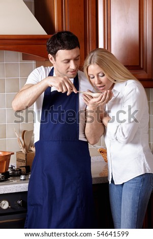 The man in an apron allows to try the cooked food to the girl