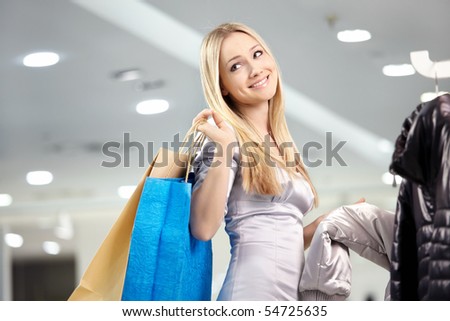 Attractive blonde smiles in outer clothing shop