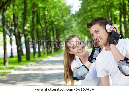 The young guy with the girl in park listens to music