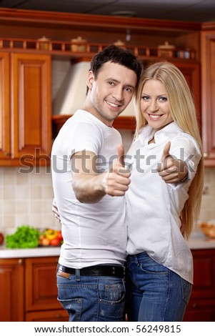 Smiling couple in kitchen with the thumbs lifted upward