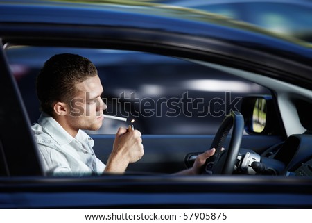 A young man lit a cigarette in a car at speed