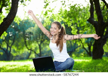 Girl with a laptop in the park with outstretched arms