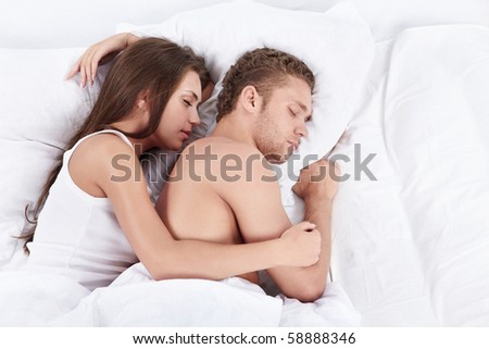 Young couple embracing in bed asleep