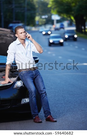 The young man next to a smashed car on the phone
