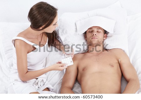 An attractive young woman holding tablet and the water in front of male patients in bed