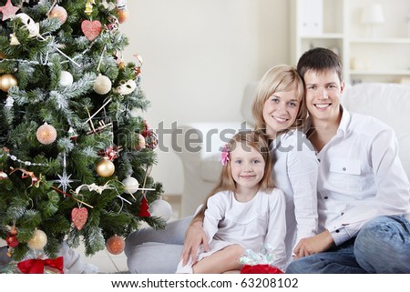 Young happy family at the Christmas tree at home