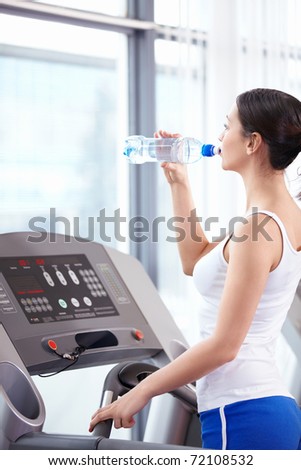 Young attractive girl drinks water in the fitness club