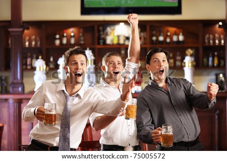 Young people with beer watching football in a bar