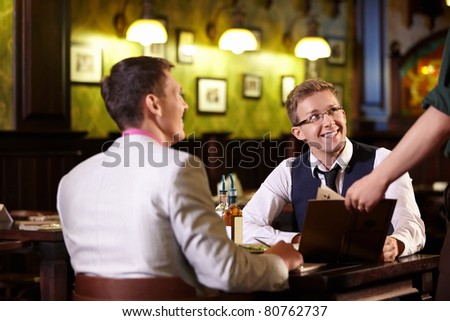 The waiter shows men in a pub menu