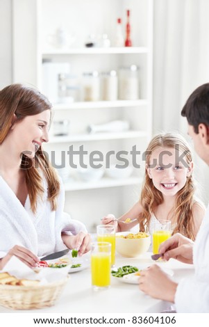 A happy family with a child eat breakfast in the kitchen