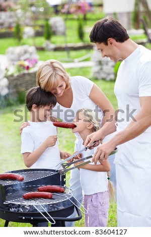 Happy family cooks sausages outdoors
