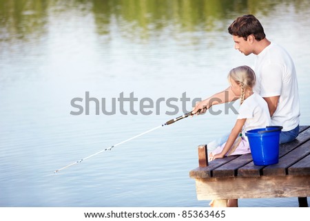 Father and daughter go fishing on the lake