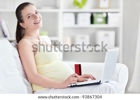 Young pregnant woman with laptop and credit card