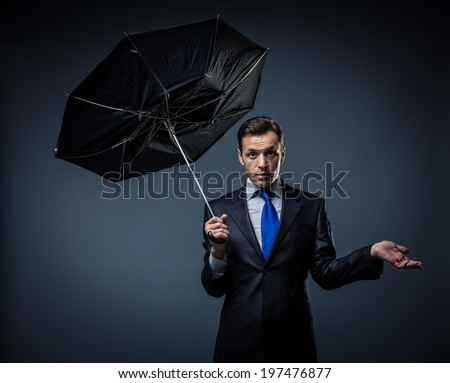 Man in a suit with a broken umbrella