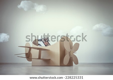 Little boy with a cardboard airplane indoors Little boy with a cardboard airplane indoors
