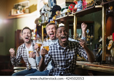 Shouting fans with a beer at a bar