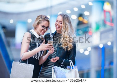 Smiling girls with mobile in a store