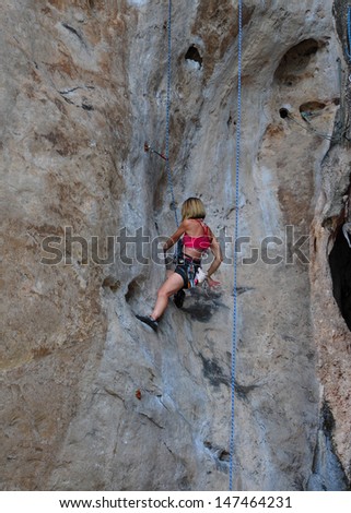 woman climbing on the rock route summer (Railay Beach, Krabi province Thailand).