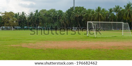 soccer goal at the end of a empty field at a park.