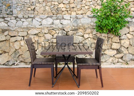 Rattan table and chairs in cafe against stone wall.