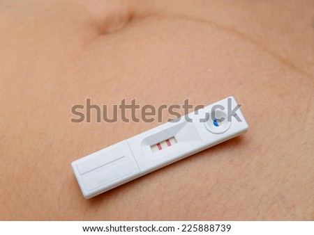 holding positive pregnancy test with two red stripes.
