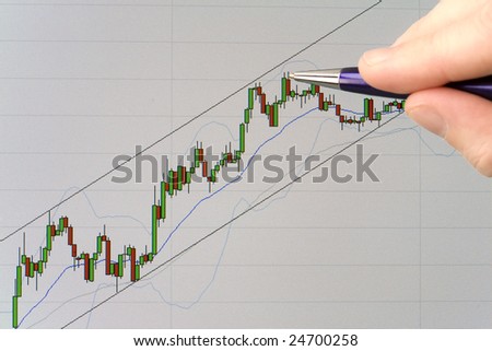 Pointing with pen at a candlestick stock price chart displayed on a computer screen