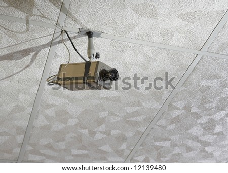 Security surveillance camera hanging from drop ceiling