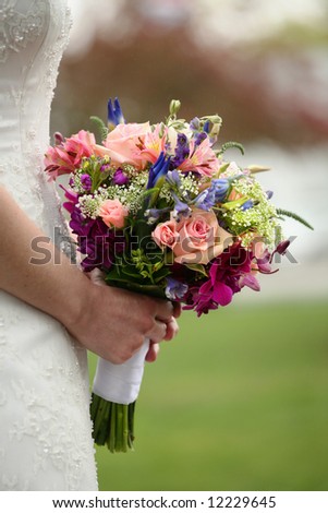 Bride holding colorful wedding bouquet against gown