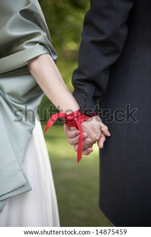 Hands tied with ribbon at traditonal handfasting wedding ceremony