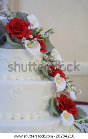 stock photo White wedding cake with red roses on table at reception