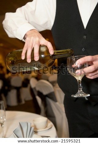 Waiter pouring glass of champagne at formal party