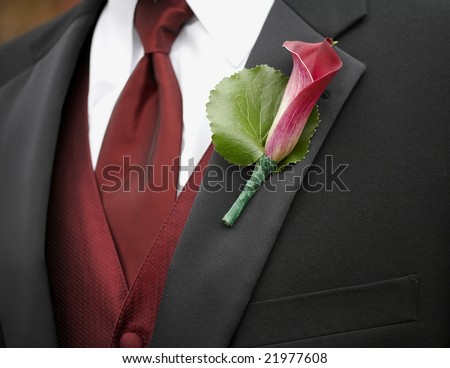 Red calla lily boutonniere on suit jacket of groom