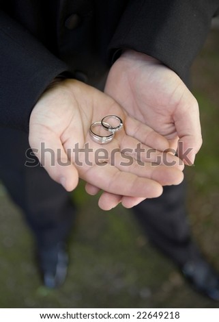 Man\'s hands holding wedding bands focus on rings