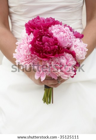 stock photo Bride holding red and pink wedding bouquet against gown