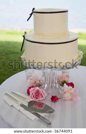 stock photo White wedding cake with roses at reception table outside