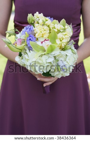 stock photo Bridesmaid holding colorful wedding bouquet against purple