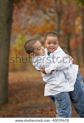 Happy young hispanic boy brothers hugging outside in foliage