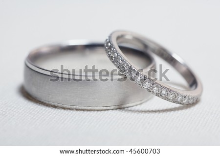 stock photo Pair of silver wedding rings on white linen focus on diamonds
